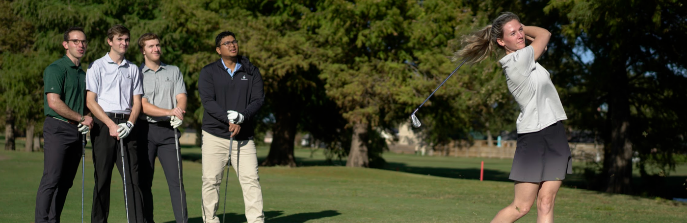A golfer taking a full swing while friends watch